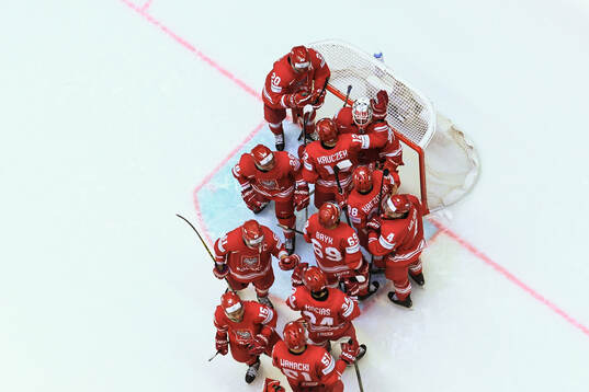 Goaltender David Zabolotny of Poland is embraced by