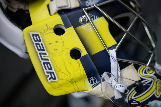 Goaltender Filip Gustavsson shows his helmet, with his