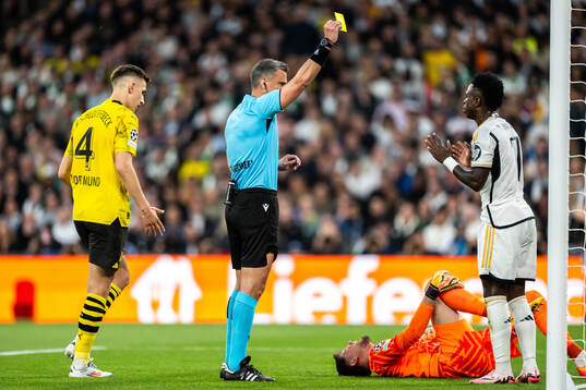 Vinicius Junior of Real Madrid receives a yellow card