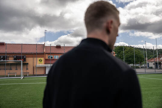 s logotyp syns på en byggnad på Jonsered IP bakom
