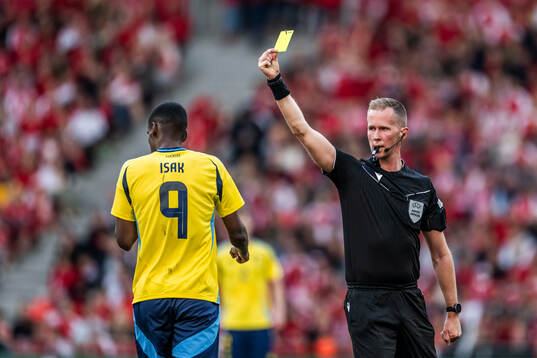 Alexander Isak of Sweden receives a yellow card from