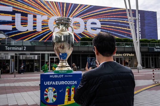 A man takes a photo of a sign with a trophy replica