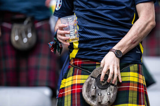A man in a kilt holding a beer
