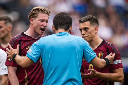 Kevin De Bruyne and Leandro Trossard of Belgium react