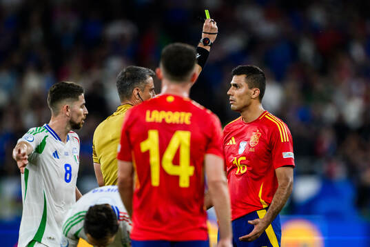 Rodrigo Hernandez of Spain receives a yellow card