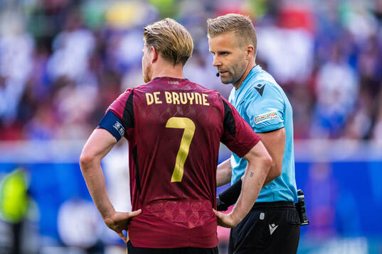 Referee Glenn Nyberg and Kevin De Bruyne of Belgium