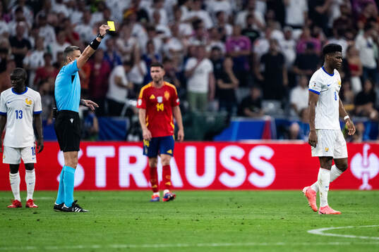 Aurélien Tchouameni of France receives a yellow card from