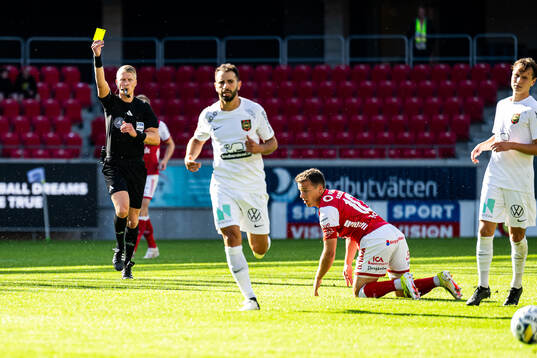 Domare Adam Ladebäck ger ett gult kort till