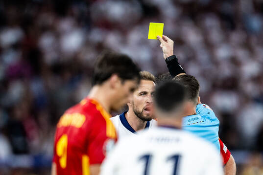 Harry Kane of England receives a yellow card from referee