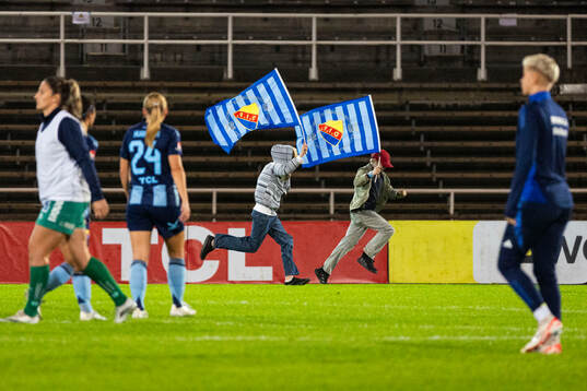 Unga Djurgårdens supportrar med flaggor storma planen