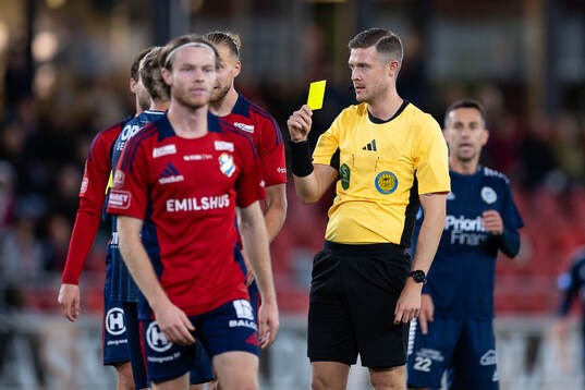 Domare Erik Mattsson delar ut ett gult kort