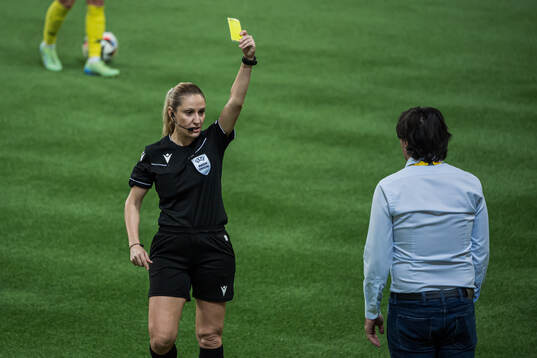 Referee Eleni Antoniou show the yellow card to Head coach