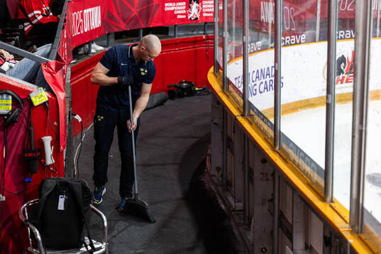 Equipment manager Jonas Landström sweeps the floor