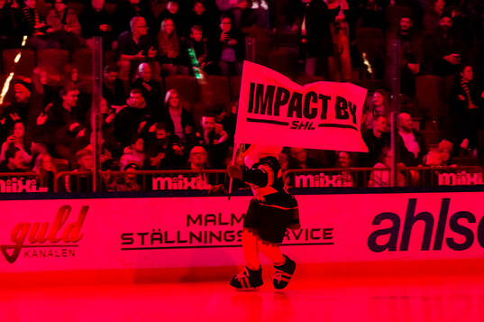 Malmö Redhawks maskot Hawkan med en Impact by SHL-flagga