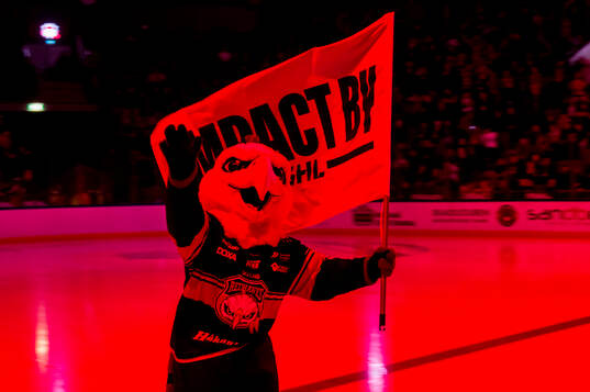 Malmö Redhawks maskot Hawkan med en Impact by SHL-flagga