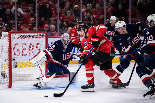 Goaltender Connor Hellebuyck of USA is being challenged by