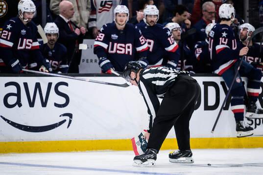A linesman picks up an item that was thrown onto the ice