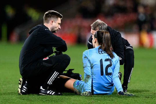 Goalkeeper Olivia Clark of Wales receives medical attention