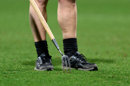 A steward repairs the pitch at halftime
