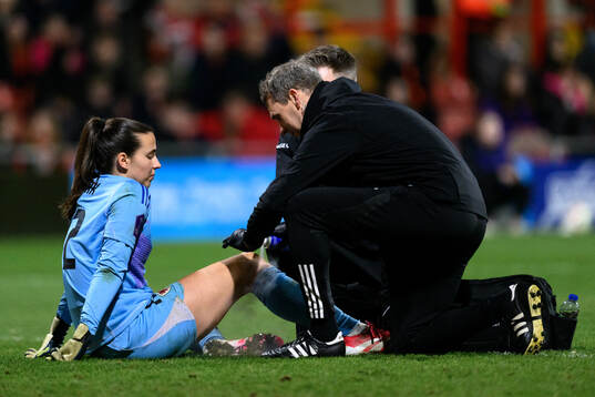 Goalkeeper Olivia Clark of Wales receives medical attention