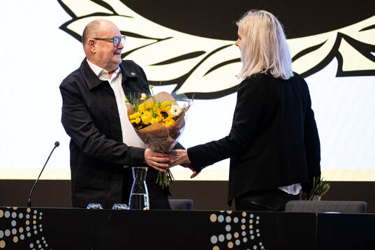 Mötesordförande Pelle Höög får blommor av ekonomichef