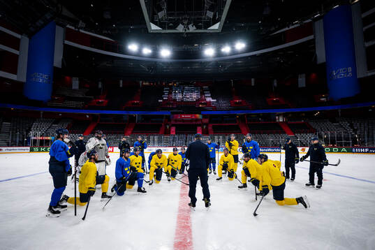Players of Sweden gather around head coach Sam Hallam at a
