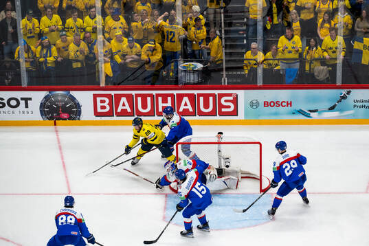 Elias Lindholm of Sweden competes for the puck with Mario