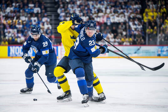 Simon Edvinsson of Sweden competes for the puck with Ahti