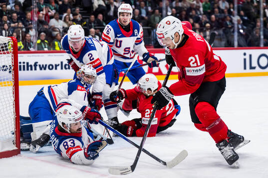 Goaltender Jeremy Swayman and Conor Garland of USA defend