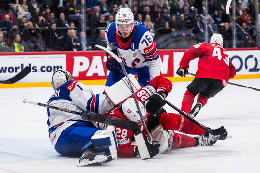 Goaltender Jeremy Swayman and Brady Skjei of USA compete