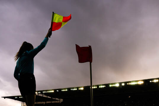 A lineswoman referee waves the flag