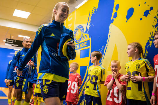 Amanda Ilestedt of Sweden walk by mascots in the player