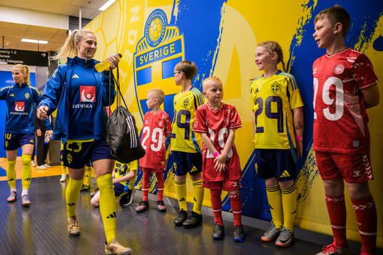 Rebecka Blomqvist of Sweden walk by mascots in the player