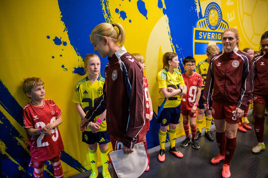 Pernille Harder of Denmark next to mascots in the player