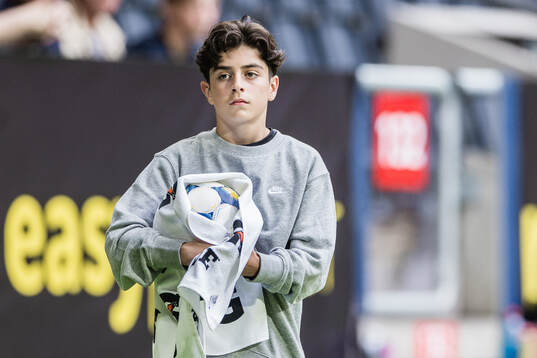 En bollkalle torkar en matchboll med handduk