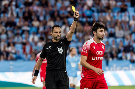Giorgi Tabatadze of FC Iberia is shown a yellow card from