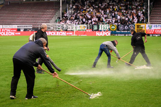 Officials remove water from the pitch