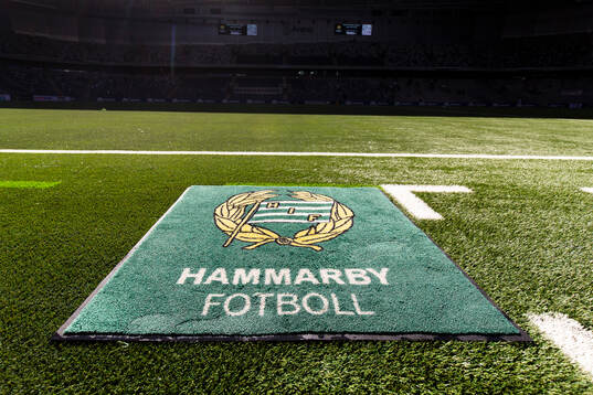 En matta med Hammarbyls klubbmärke ligger på konstgräset