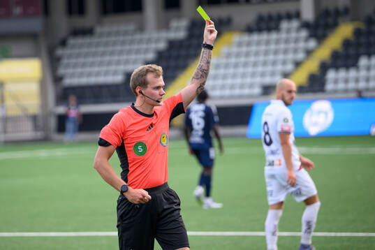 Domare Fredrik Alknäs visar upp ett gult kort