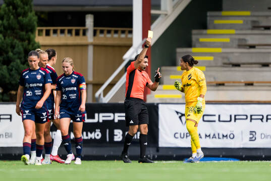 Domare George Jansizian dömer gult kort och AIKs målvakt