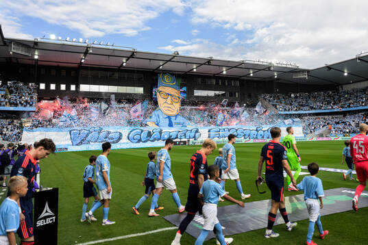 Spelare framför Malmös supportrars tifo föreställande