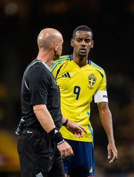 Alexander Isak of Sweden and referee Anthony Taylor