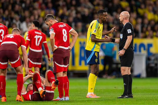 Alexander Isak of Sweden and referee Anthony Taylor