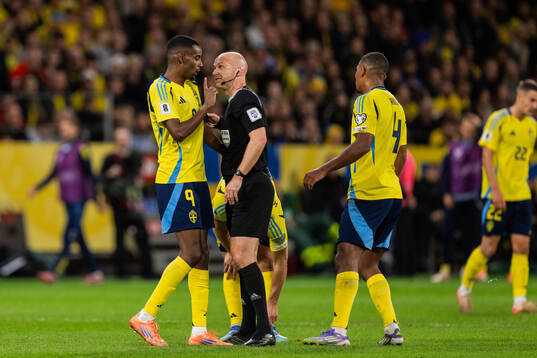 Alexander Isak of Sweden and referee Anthony Taylor