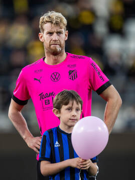 Häckens Filip Helander med en maskot som håller i rosa
