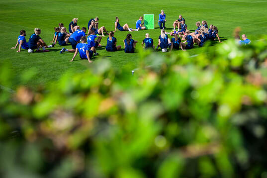 Players gather around head coach Gemma Grainger of the