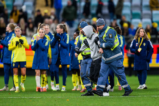 A pitch invader is taken by security