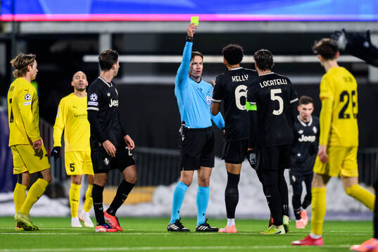 Lloyd Kelly of Juventus is shown a yellow card by Danny