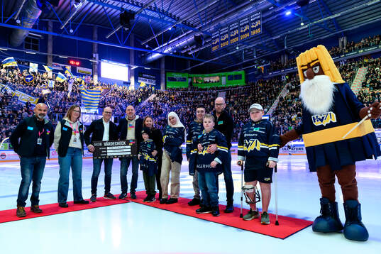 HV71 delar ut en check till representanter från Min Stora