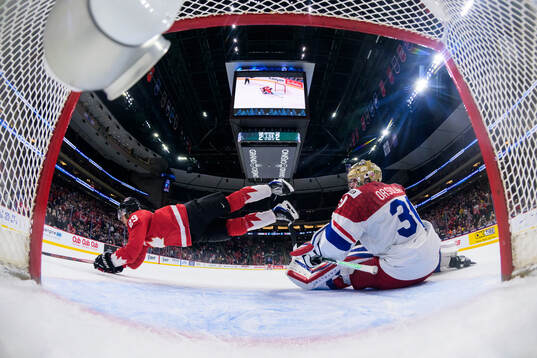 Michael Hage of Canada is being tripped by goaltender